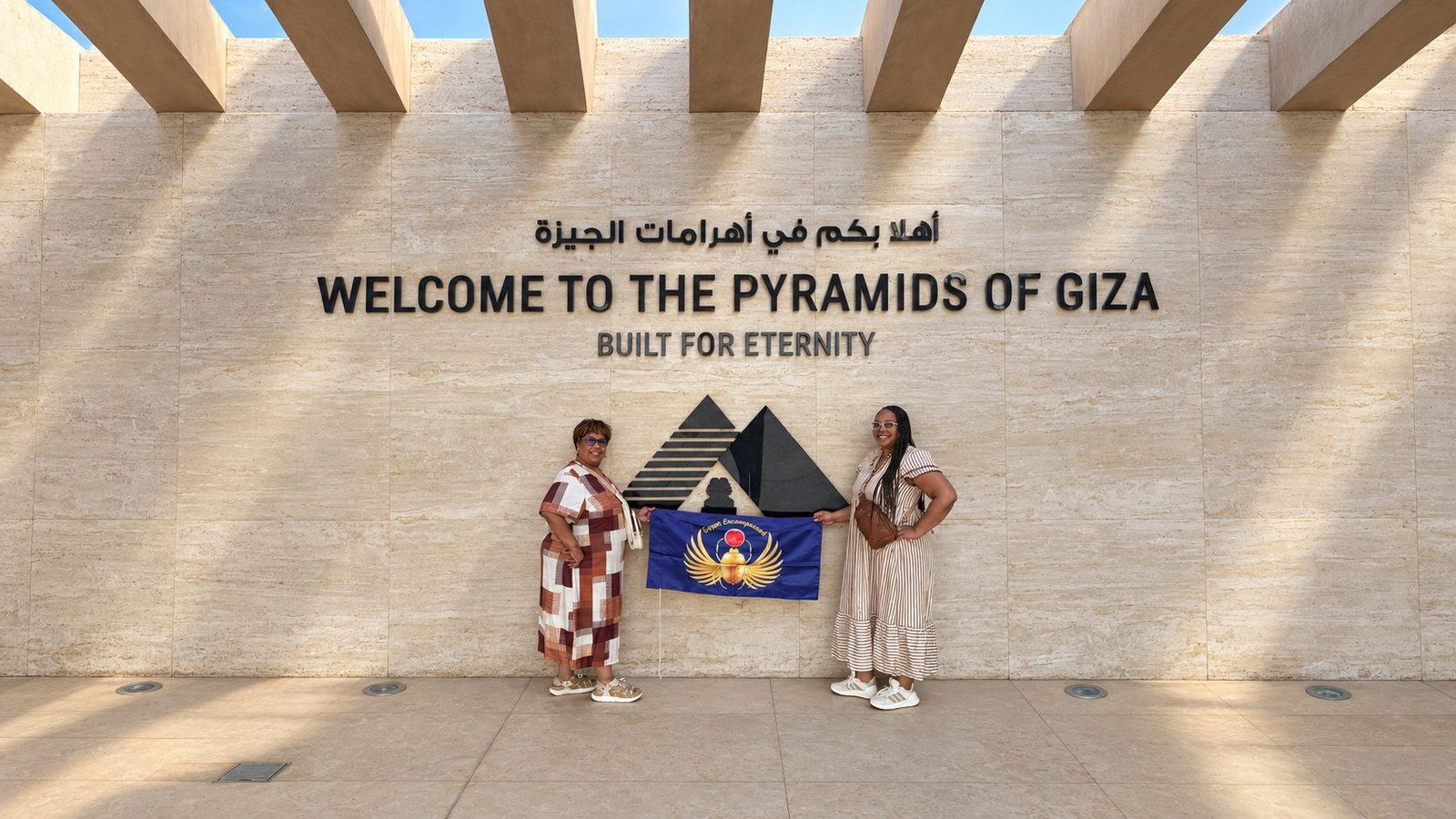 Two guests holding an Egypt Encompassed flag at the Pyramids of Giza entrance