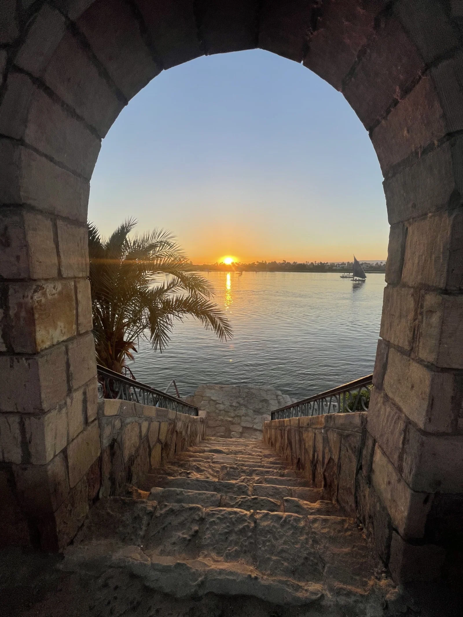 Sunset over the Nile framed by a historic stone arch